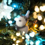 Close-up of a reindeer ornament on a Christmas tree with festive bokeh lights, capturing holiday spirit.